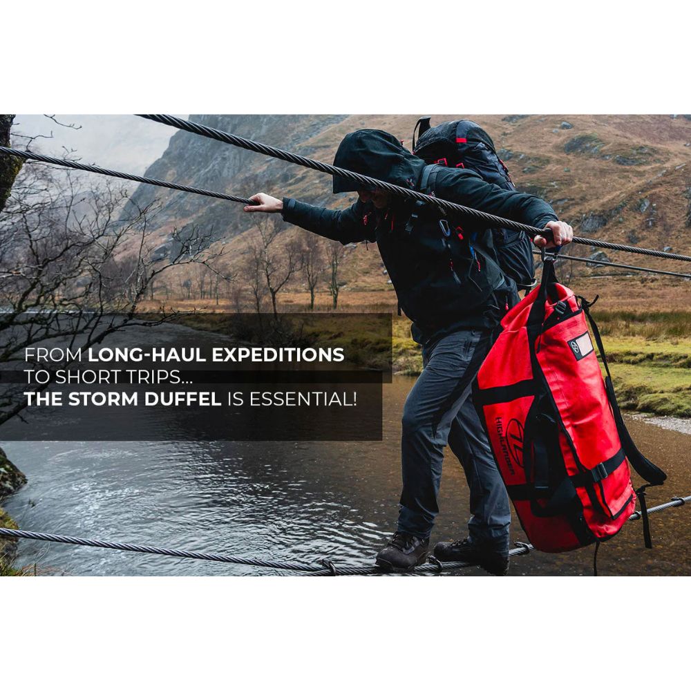 Adventurer carrying a red Highlander Storm Kit Bag, showcasing its durability and practicality for any expedition.