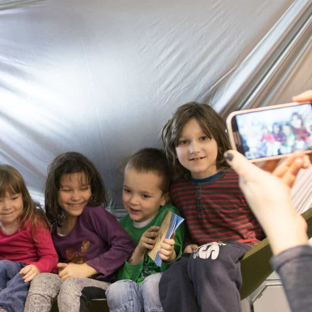 Four children smiling in a tarp hammock.