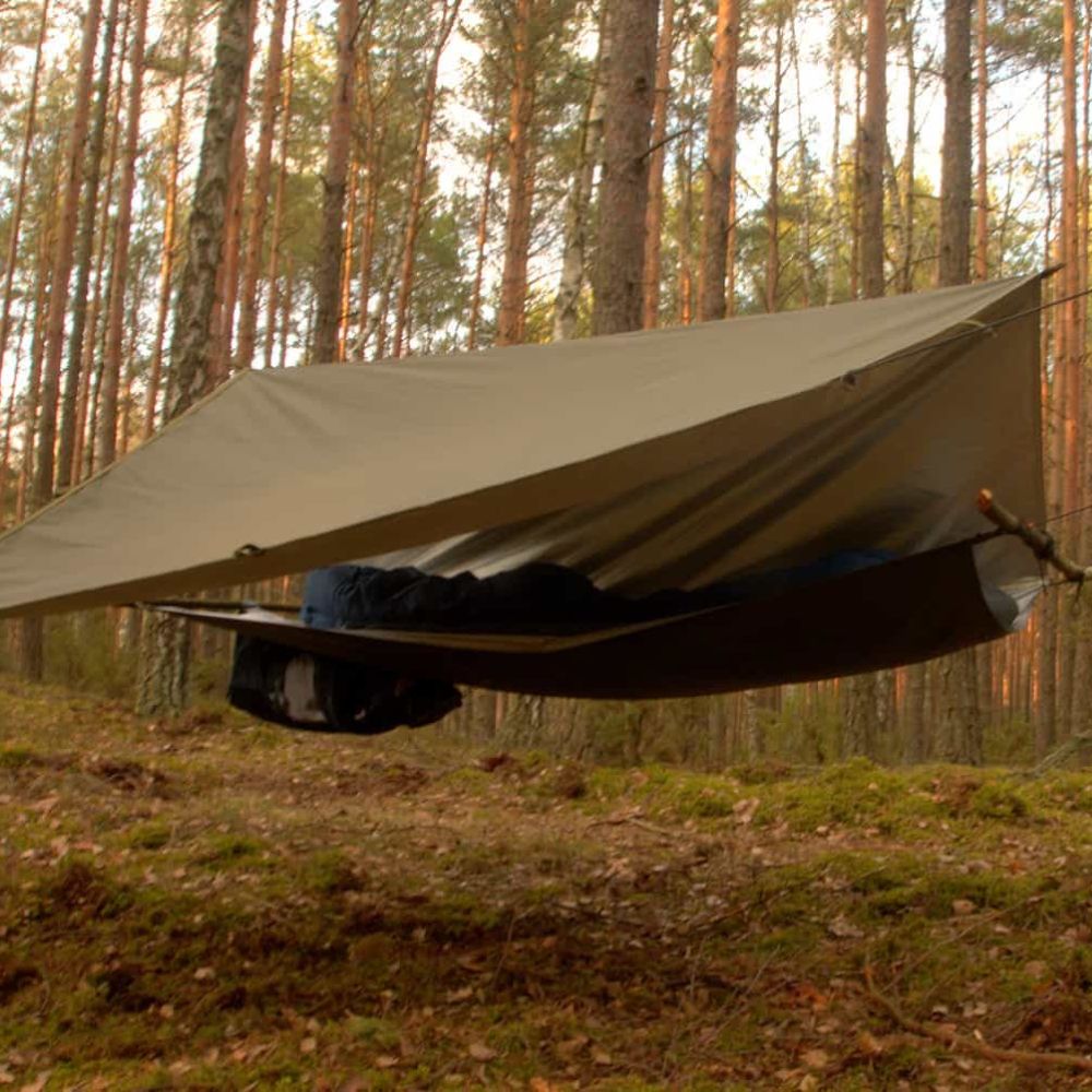 Thermo-tarp set up as a hammock in a forest.