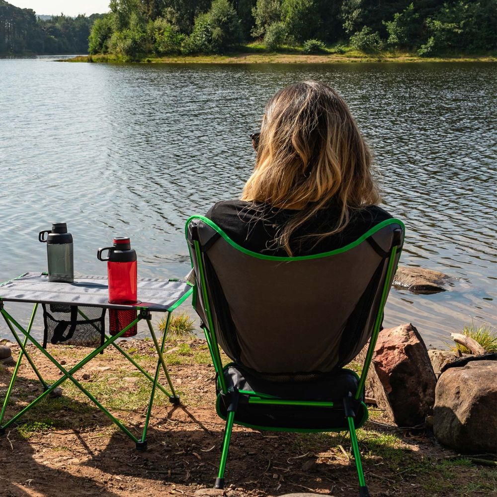 A person relaxes in a green and grey Highlander Ayr Folding Camping Chair.