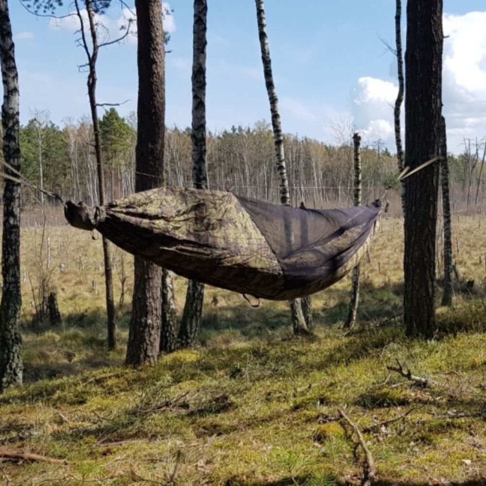 Hammock hanging in a forest with camouflage design.