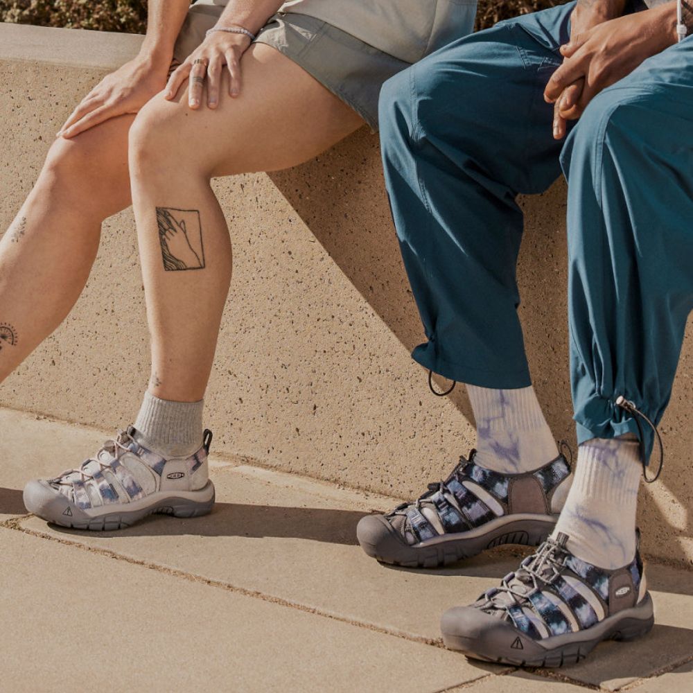 Two people wearing KEEN Newport H2 sandals, one in a magnet tie-dye pattern.