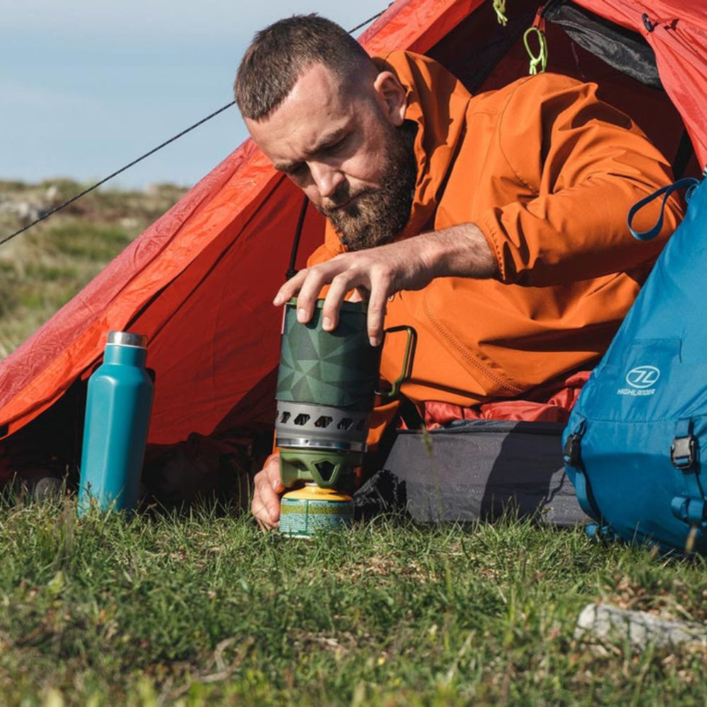 Man using olive blade fastboil 3 camping gas stove near a tent.