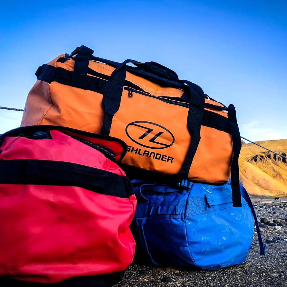 Stacked Storm Kitbags in orange, red, and blue outdoors.