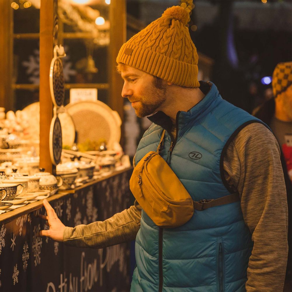 Man wearing a blue vest and mustard Targa bum bag browsing a ceramic market stall.